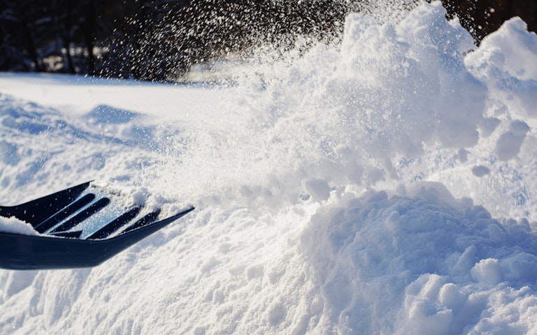 Man throwing snow while cleaning. Removing snow with shovel in a