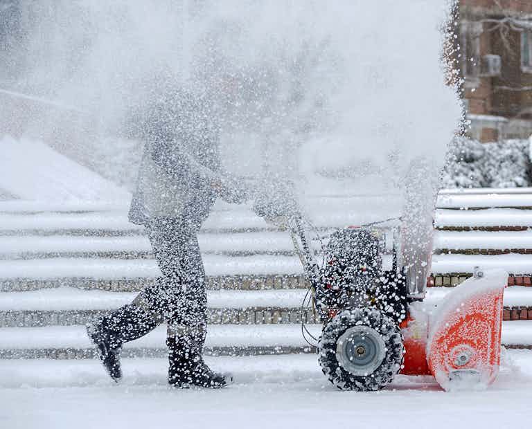 Snow-removal work with a snow blower. Man Removing Snow. heavy precipitation and snow piles.