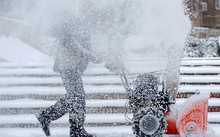 Snow-removal work with a snow blower. Man Removing Snow. heavy precipitation and snow piles.